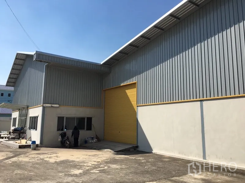 Warehouse for rent in Saphan Sung, Bangkok - Close-up of warehouse entrance with high yellow roller door and loading apron.