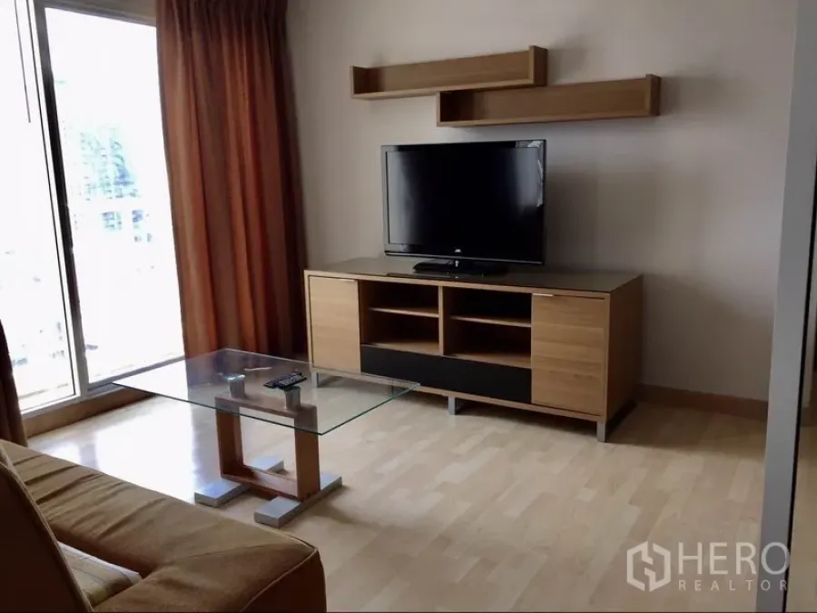 Condominium for rent in Watthana, Bangkok - TV console and floating shelves in the lounge with large window and curtains.