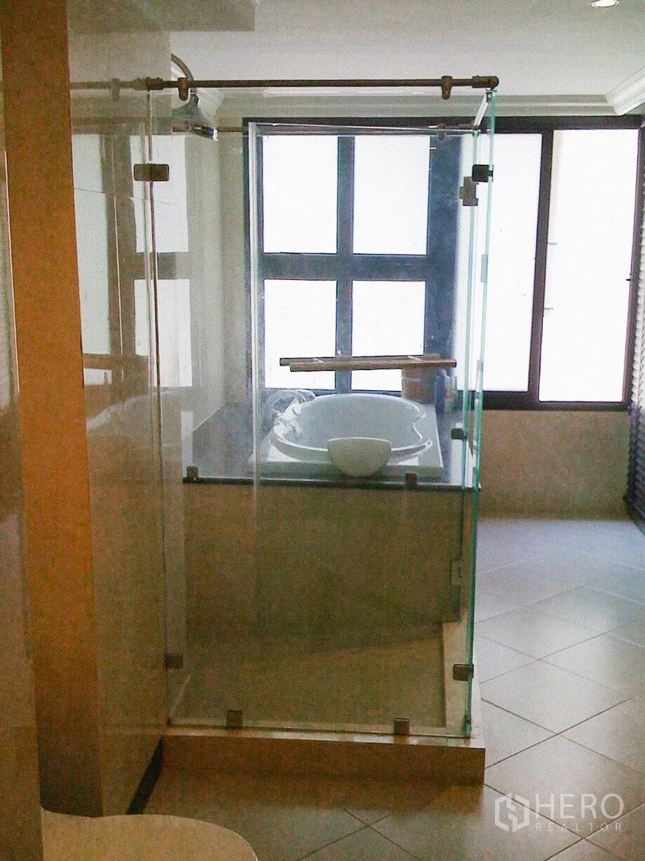 Townhouse for rent in Khlong Toei, Bangkok - Bathroom with separate glass shower and soaking tub beside frosted windows.