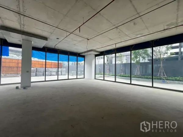 Retail Space for rent - Bright shell retail interior with floor-to-ceiling corner glass, high concrete ceiling and open plan facing a landscaped walkway in Phaya Thai, Bangkok.