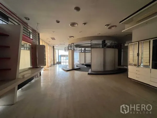 Retail Space for rent - Spacious retail showroom with circular display structure, built-in shelving, wood flooring and floor-to-ceiling windows.