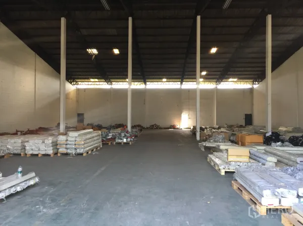 Factory for rent in Pathum Thani - Spacious factory interior with high steel roof, tall columns and stacked pallets on the floor.