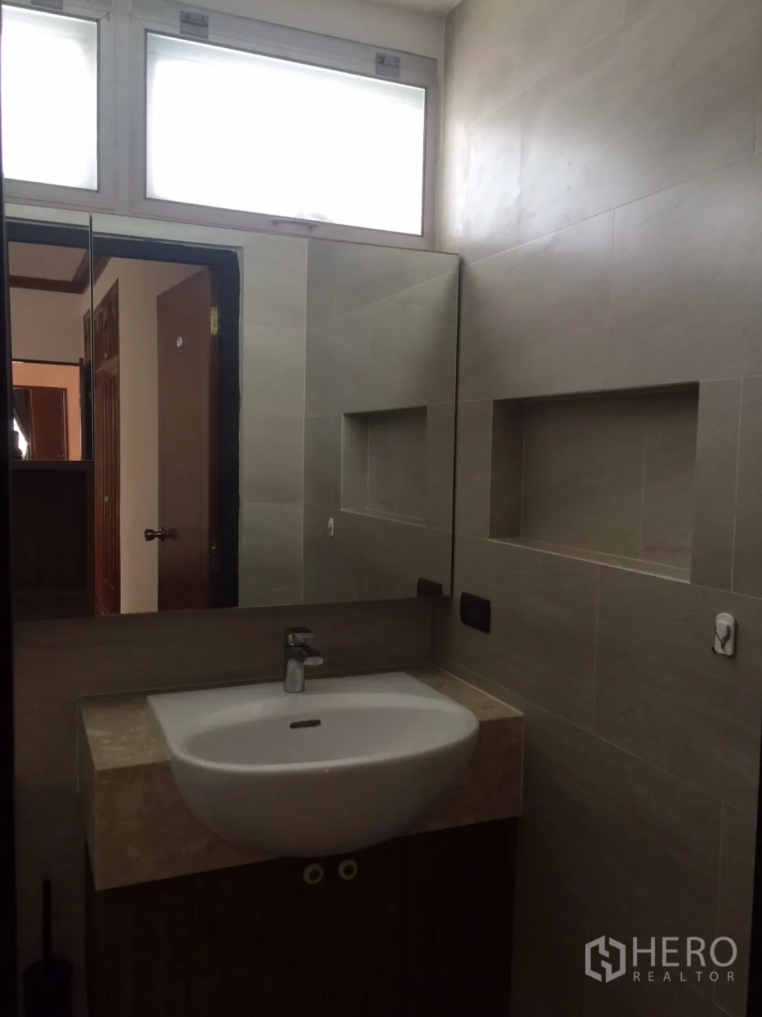 Detached House for rent in Khlong Toei, Bangkok - Contemporary bathroom with wide mirror, vanity and neutral tiles.