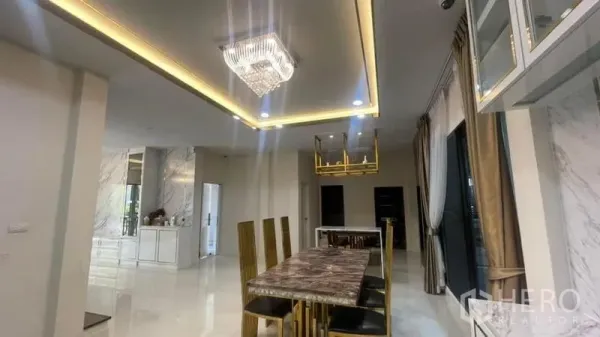 Detached House for rent or sale in Prawet, Bangkok - Dining area with marble-top table, gold chairs, recessed lighting and chandelier in a modern home.