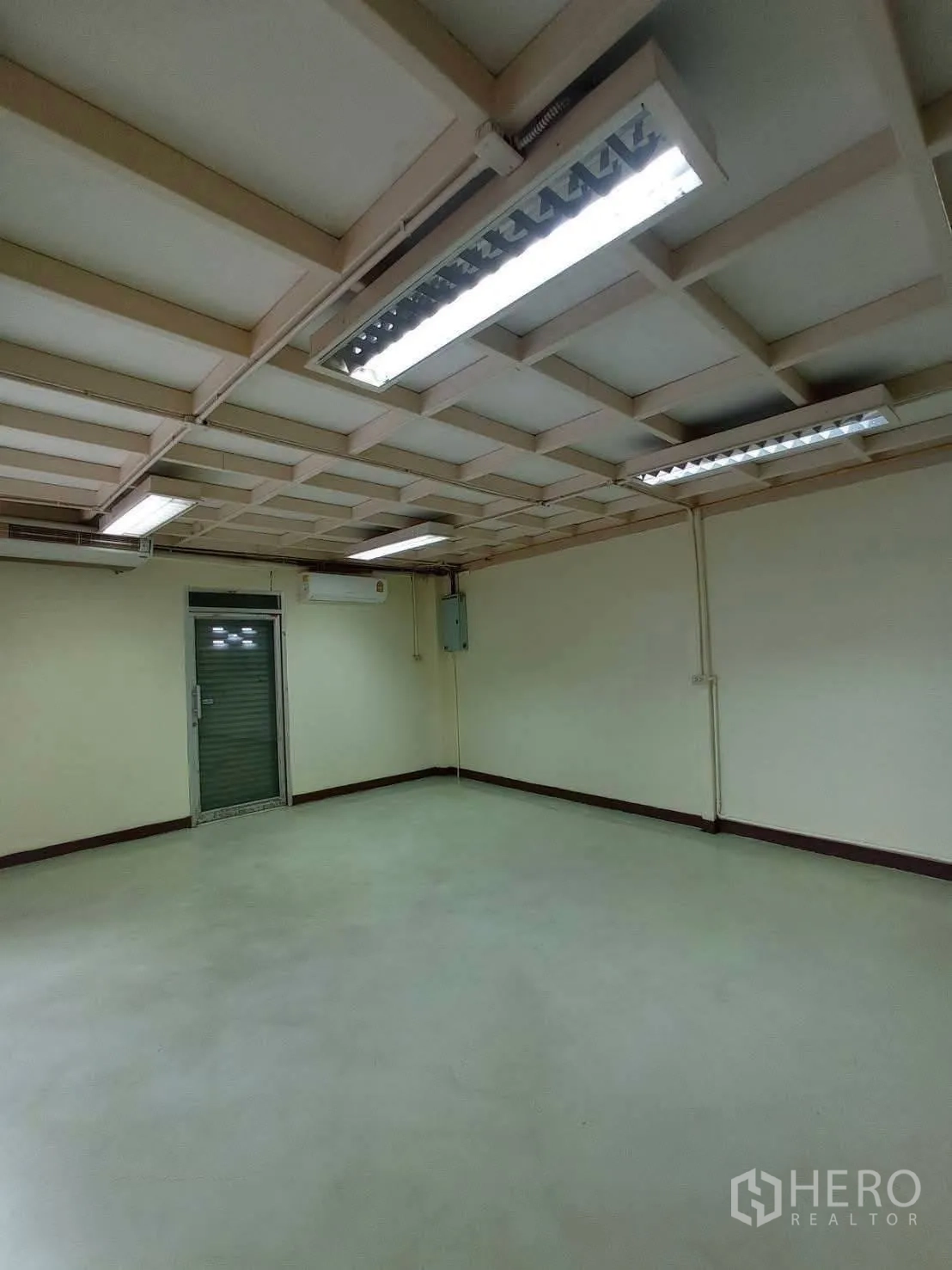 Warehouse for rent in Suan Luang, Bangkok - Office room from another angle showing drop ceiling and rear metal door.