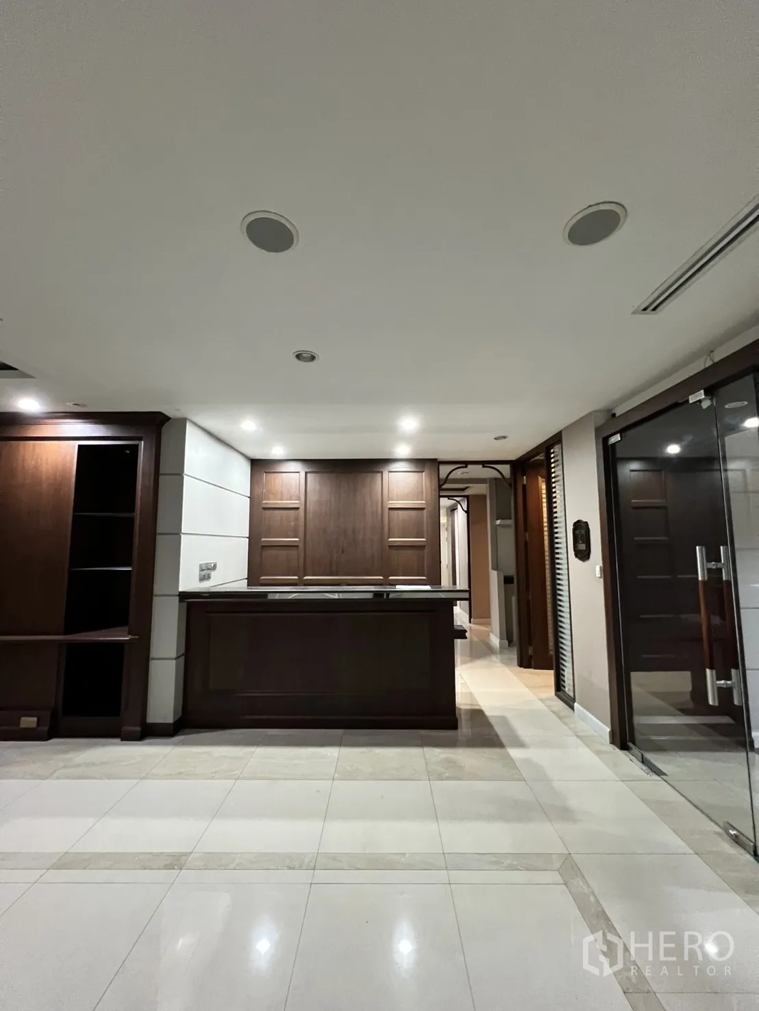 Office Space for rent in Watthana, Bangkok - Front-facing reception counter with wood cabinetry and spotlights.