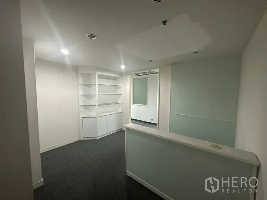 Office Space for rent in Khlong Toei, Bangkok - Reception area with counter, built‑in shelving, recessed lights and frosted glass partition.