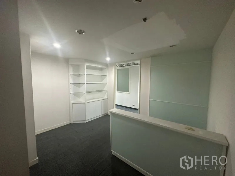 Office Space for rent in Khlong Toei, Bangkok - Reception area with counter, built‑in shelving, recessed lights and frosted glass partition.