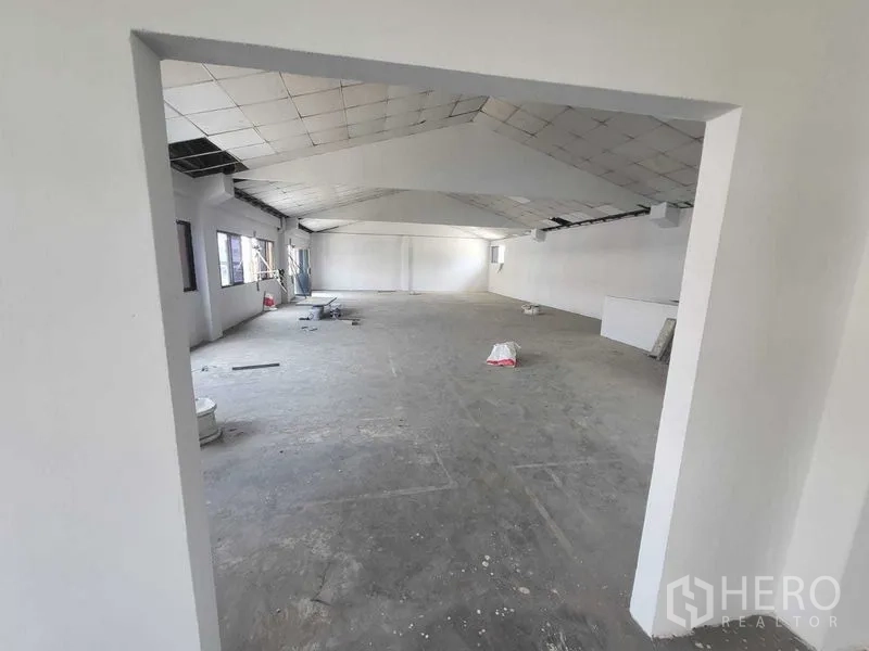 Factory for rent or sale in Samut Prakan - Entry view into expansive loft-style room with tiled ceiling and concrete floor.