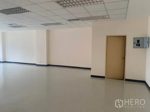 Office Space for rent in Watthana, Bangkok - Spacious office interior with drop-ceiling lights, beige utility door and wall-mounted electrical panel.