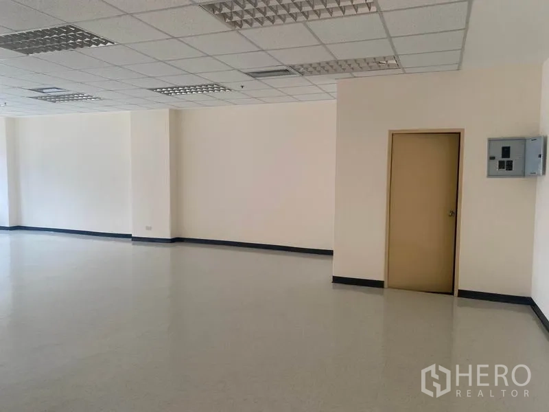 Office Space for rent in Watthana, Bangkok - Spacious office interior with drop-ceiling lights, beige utility door and wall-mounted electrical panel.