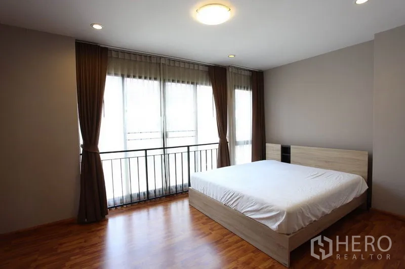 Townhouse for rent in Phra Khanong, Bangkok - Spacious master bedroom with wood flooring and large floor-to-ceiling windows.