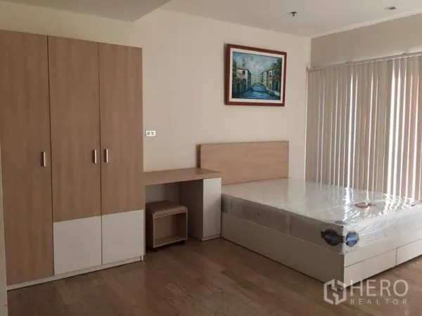 Condominium for rent in Khlong Toei, Bangkok - Sleeping zone with double bed, built-in wardrobe, work desk and vertical blinds in neutral tones.