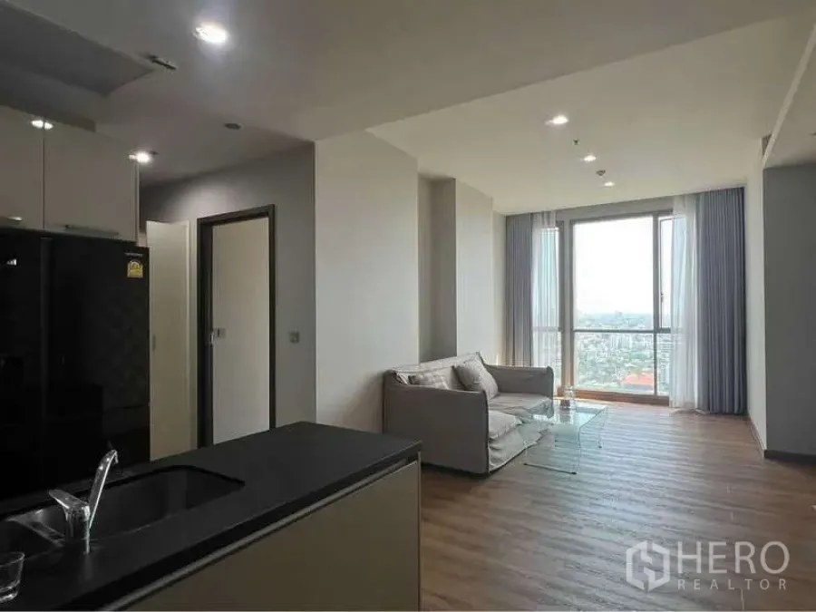 Condominium for sale in Watthana, Bangkok - Open-plan living room with wide window and high-floor city view.