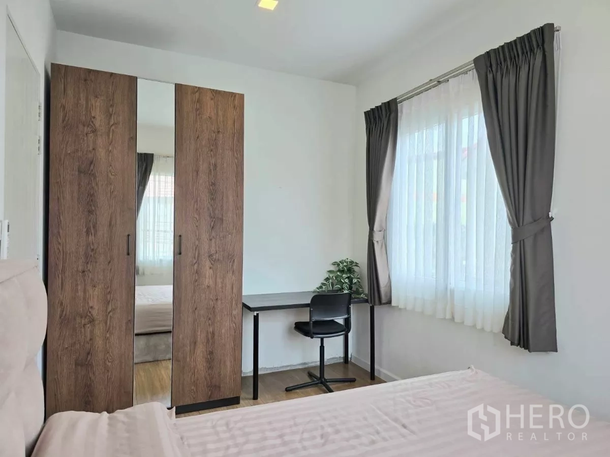 Detached House for rent in Samut Prakan - Guest bedroom with wardrobe, study desk and double windows with curtains.