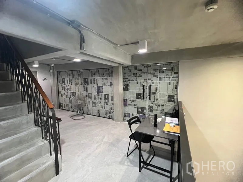 Retail Space for rent in Watthana, Bangkok - Industrial-style retail interior with exposed concrete, glass partitions, metal staircase, and compact worktable near Phrom Phong BTS.