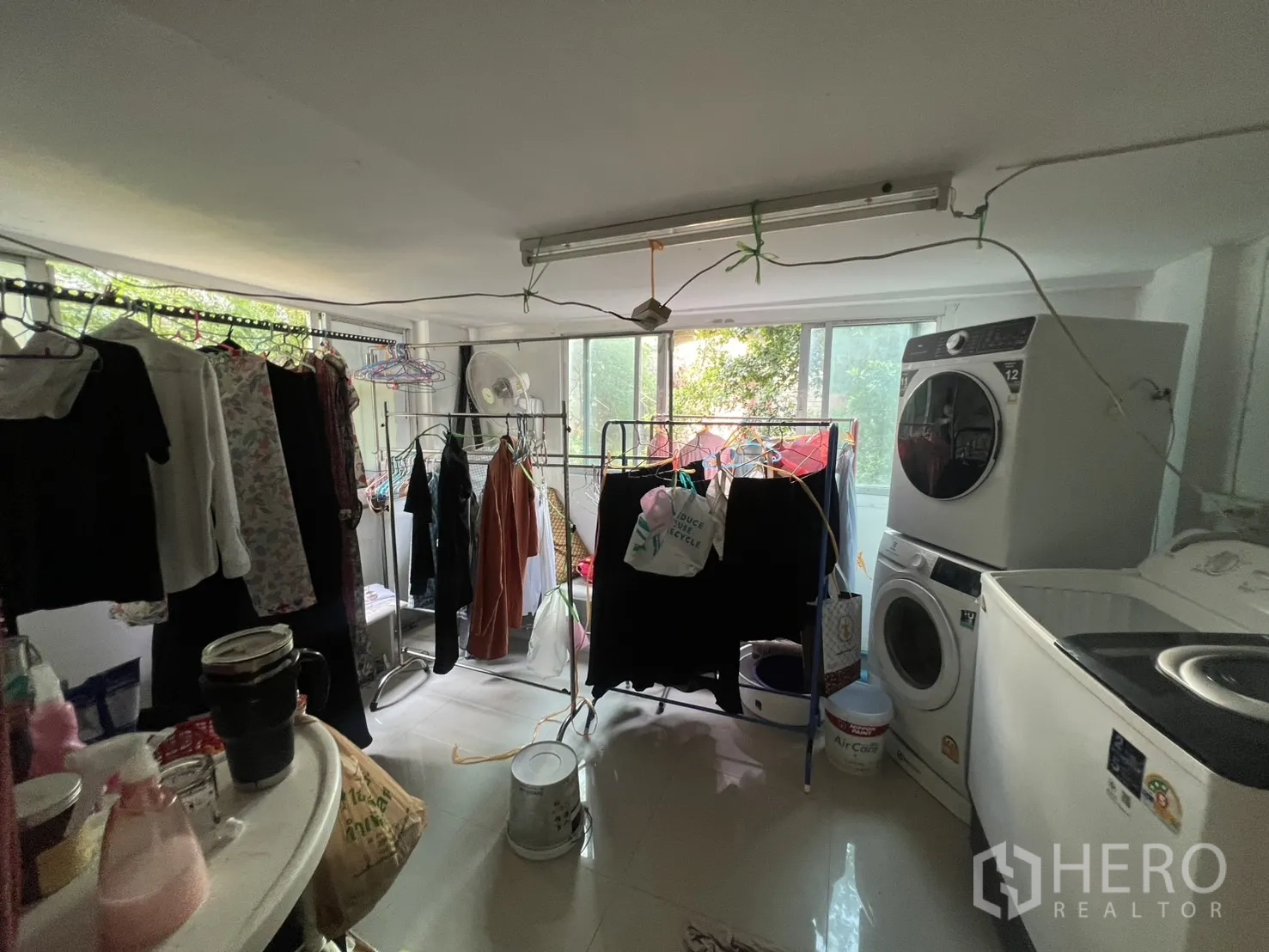 Retail Space for rent - Laundry and drying room with multiple racks and washing machines near large windows.