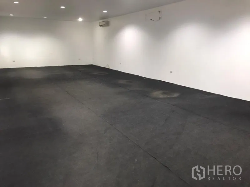 Warehouse for rent in Wang Thonglang, Bangkok - Air-conditioned office or showroom with white walls, recessed lights and dark carpet flooring.