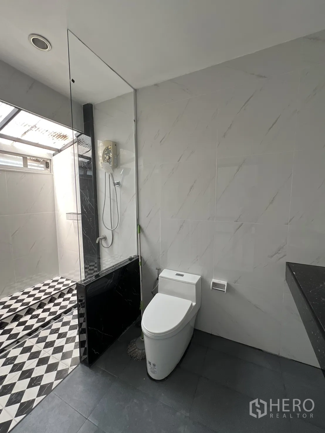 Townhouse for rent in Watthana, Bangkok - Bright bathroom with toilet and step-up shower featuring black-and-white diamond tiles.
