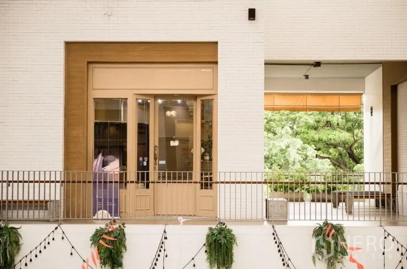 Retail Space for rent in Khlong Toei, Bangkok - Retail shopfront with glass double doors and balcony railing facing greenery.