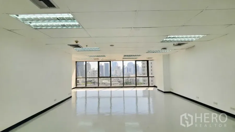 Office Space for rent in Watthana, Bangkok - Bright unfurnished office with large windows, suspended ceiling lighting, and Bangkok skyline views.