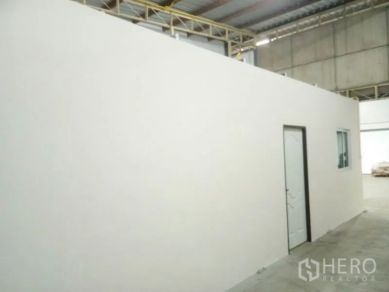 Warehouse for rent in Suan Luang, Bangkok - Side view of the office module and door beneath the metal roof structure.