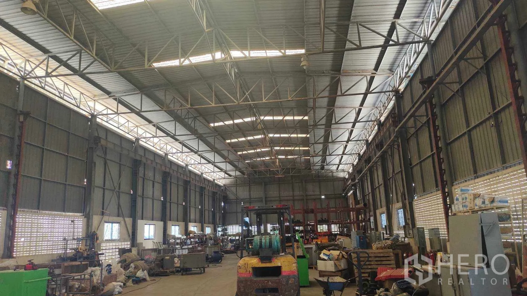 Factory for sale in Nikhom Phatthana, Rayong - High-bay zone with large sliding doors and workshop equipment.