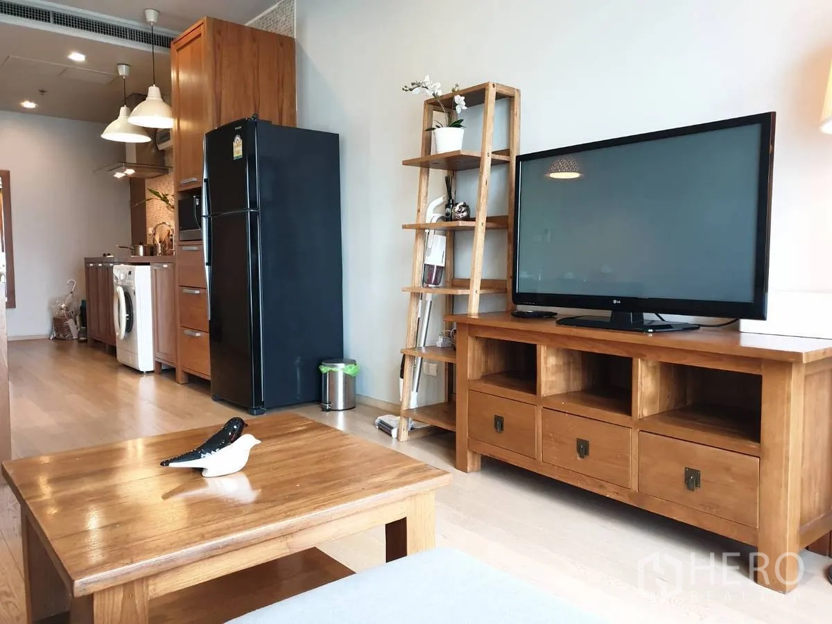 Condominium for rent or sale in Bangkok - Entertainment console with flat-screen TV beside a galley kitchen with tall pantry and fridge.