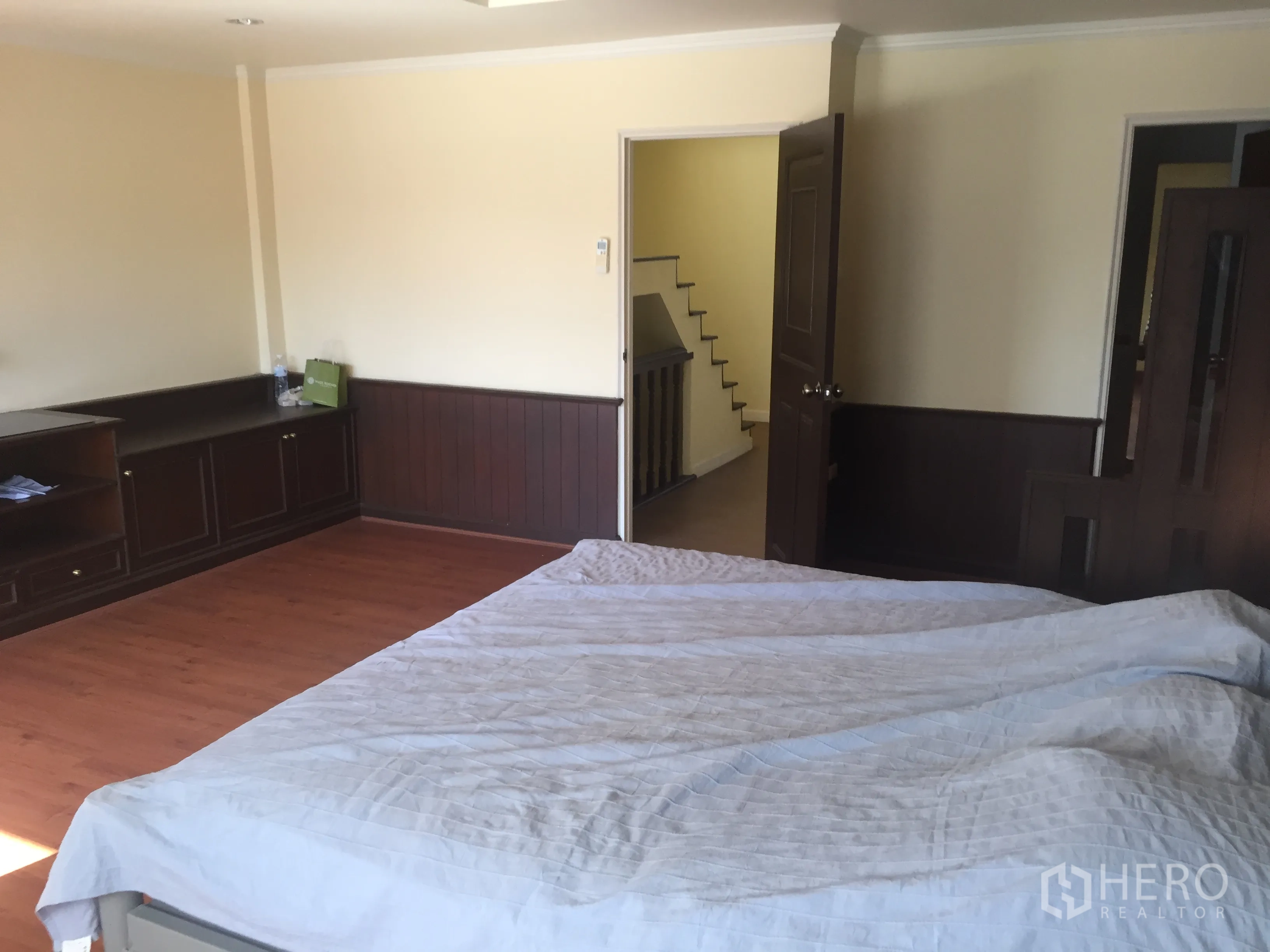 Townhouse for rent in Khlong Toei, Bangkok - Primary bedroom with wood wainscoting, built-in storage and a doorway to the stair hall.