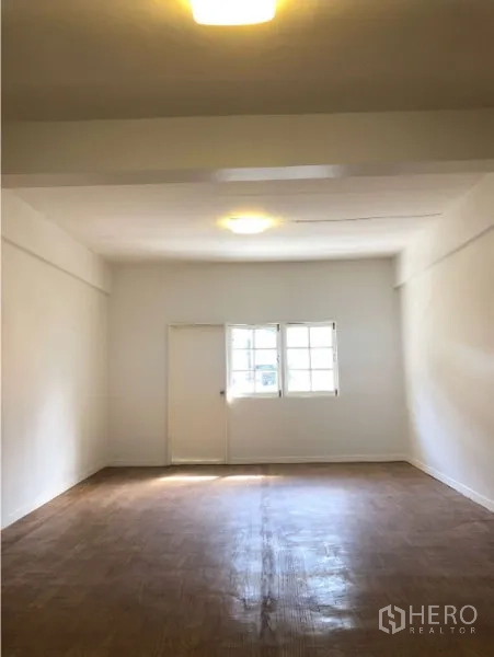 Shophouse for rent in Watthana, Bangkok - Bright upper floor room with window and wood-style flooring.