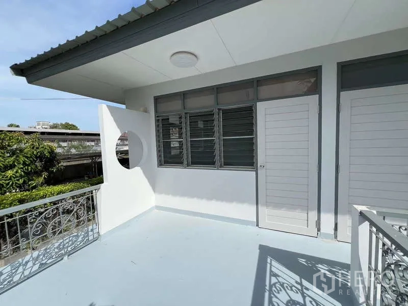 Detached House for rent in Bang Na, Bangkok - Upper-floor terrace with decorative railing and white doors beside louvered windows.