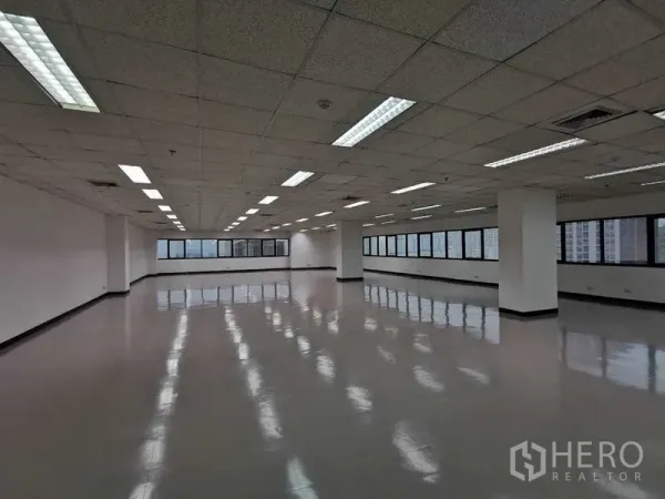 Office Space for rent in Watthana, Bangkok - Open office area with columns, strip lighting, and panoramic windows overlooking Bangkok.