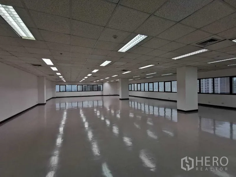 Office Space for rent in Watthana, Bangkok - Open office area with columns, strip lighting, and panoramic windows overlooking Bangkok.