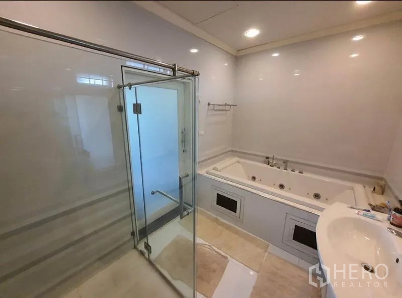 Detached House for sale in Sai Mai, Bangkok - Bathroom with built-in jacuzzi bathtub beside a glass shower enclosure and sink.