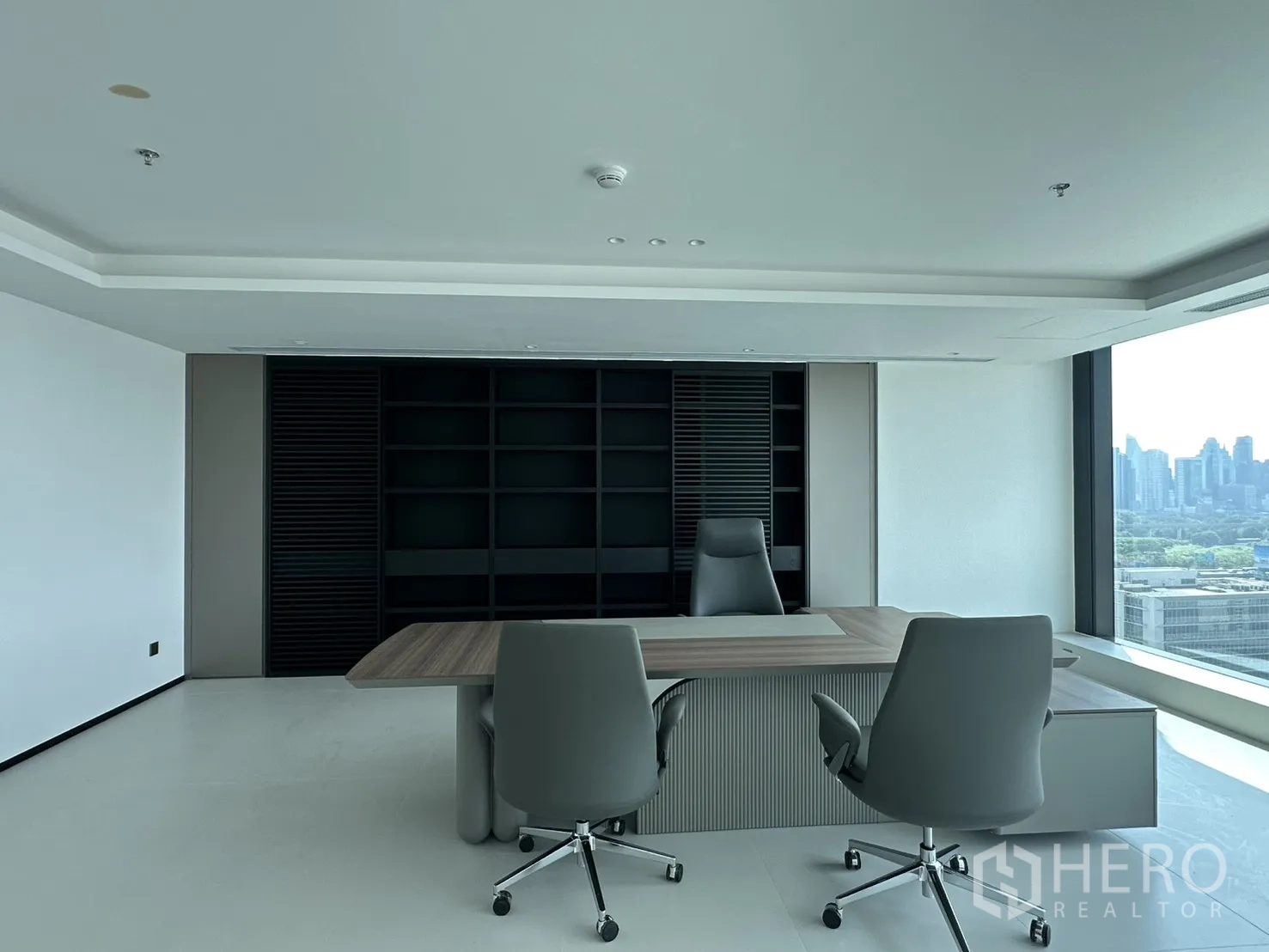 Office Space for rent in Din Daeng, Bangkok - Executive desk with guest chairs and built-in shelving, plus a side city view.
