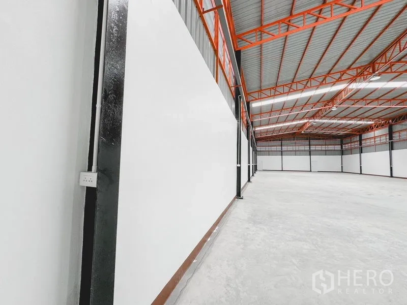 Warehouse for rent or sale in Khlong Luang, Pathum Thani - Interior wall detail showing a power outlet and the long span steel roof structure.