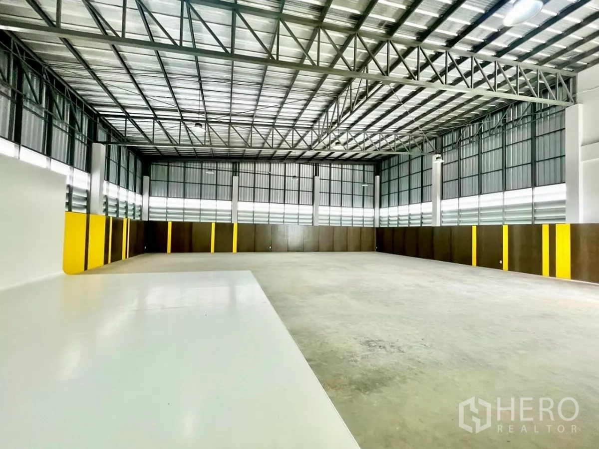 Warehouse for sale in Lam Luk Ka, Pathum Thani - Bright warehouse floor with white epoxy zone and tall windows for natural light.