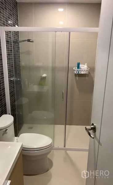 Townhouse for rent in Thanyaburi, Pathum Thani - Clean bathroom with tiled walls, toilet, vanity, and sliding glass shower.