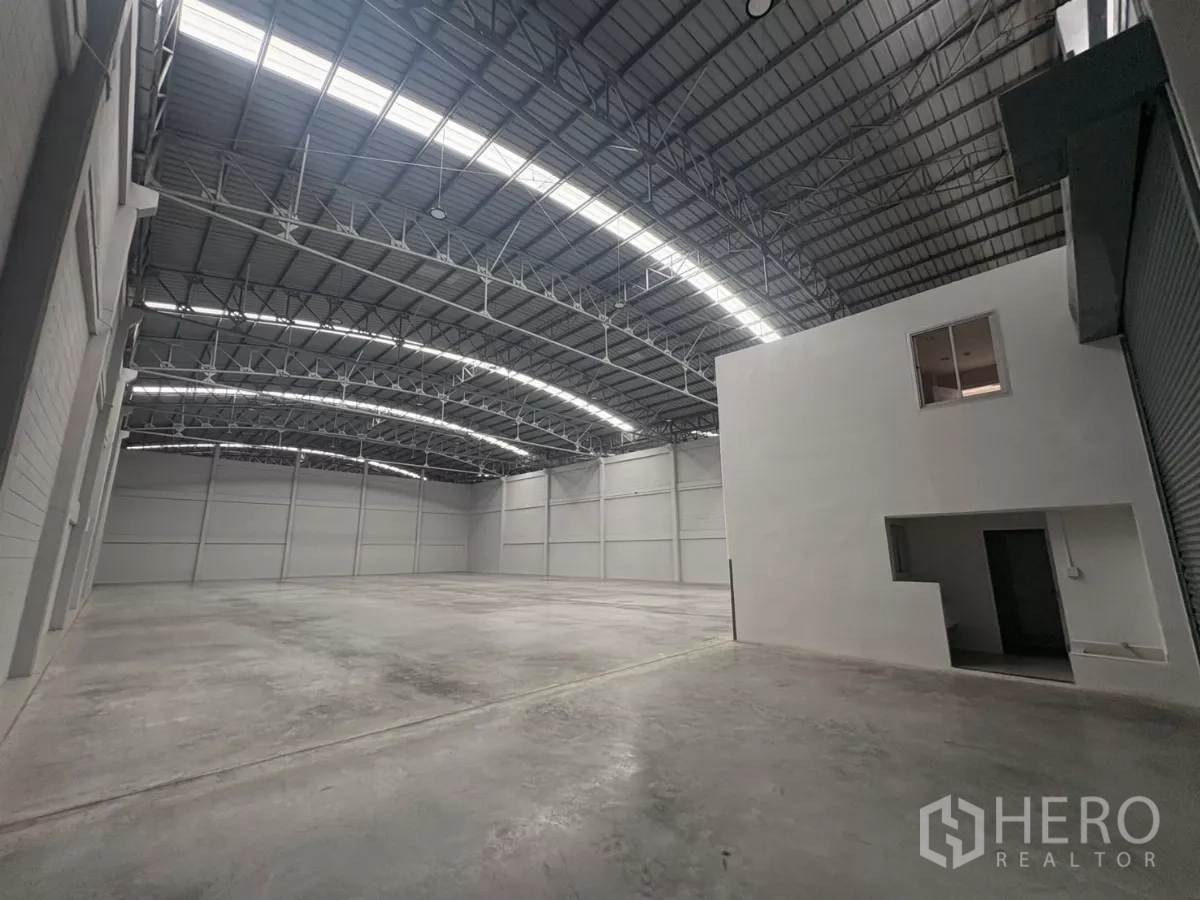 Factory for rent in Bang Phli, Samut Prakan - Warehouse interior with roller shutter entry and white mezzanine office block.