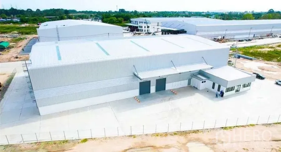 Warehouse for rent in Mueang Rayong, Rayong - Aerial view of a new steel‑clad warehouse with covered loading bays, attached office and fenced concrete yard.