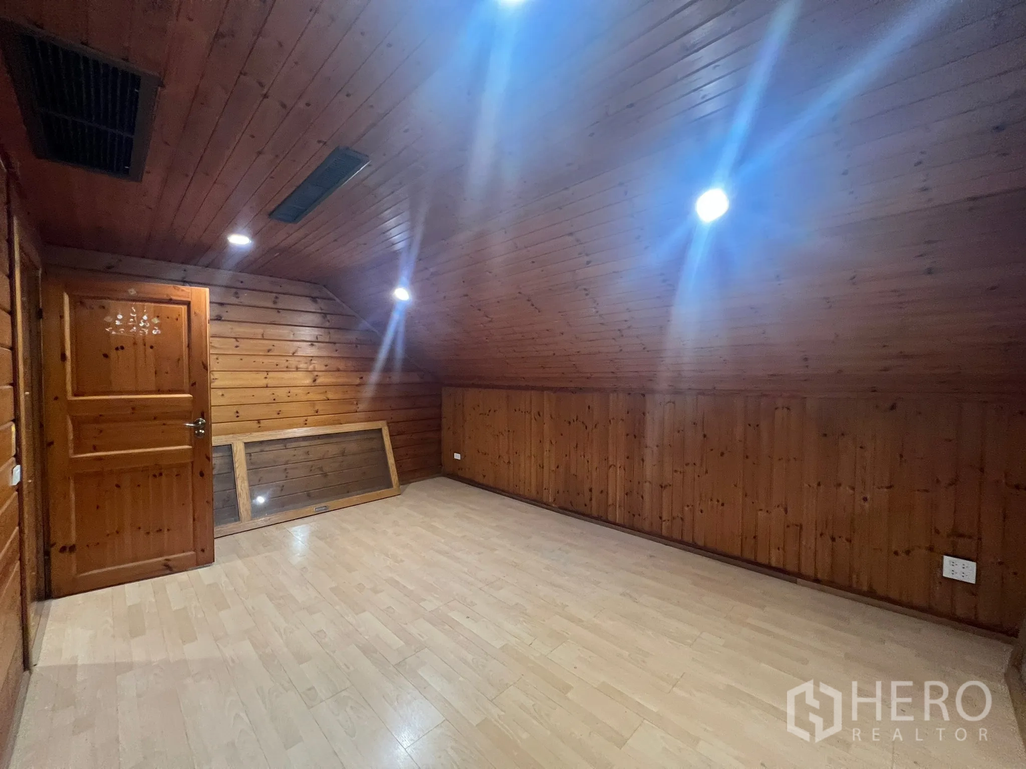 Home Office for rent in Suan Luang, Bangkok - Spacious attic-style room with timber walls, a door and ceiling downlights.
