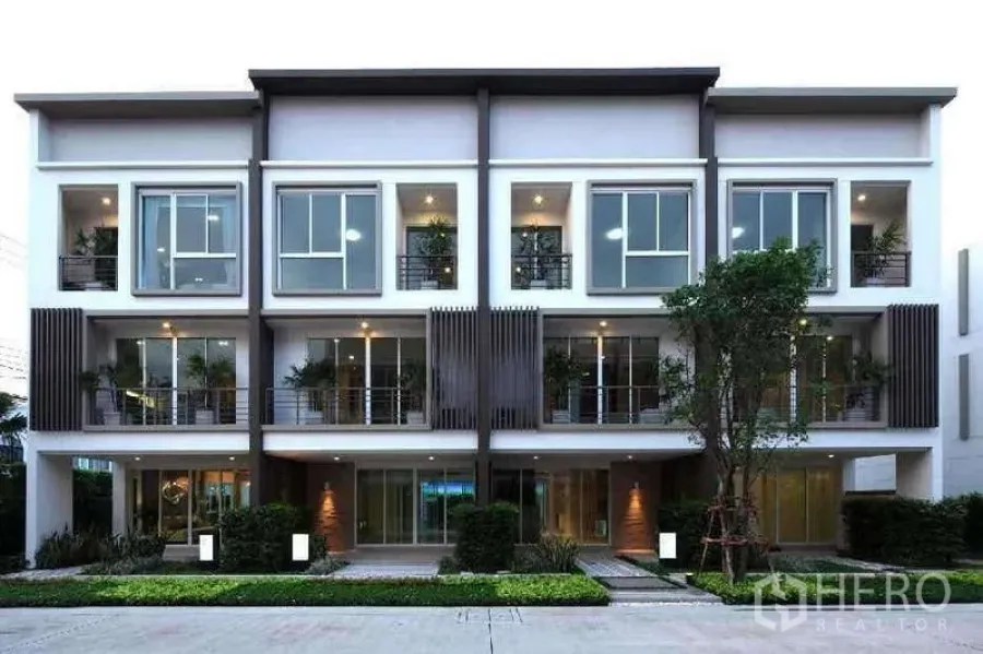 Home Office for rent in Chatuchak, Bangkok - Row of modern three-storey townhomes with landscaped frontage at dusk.