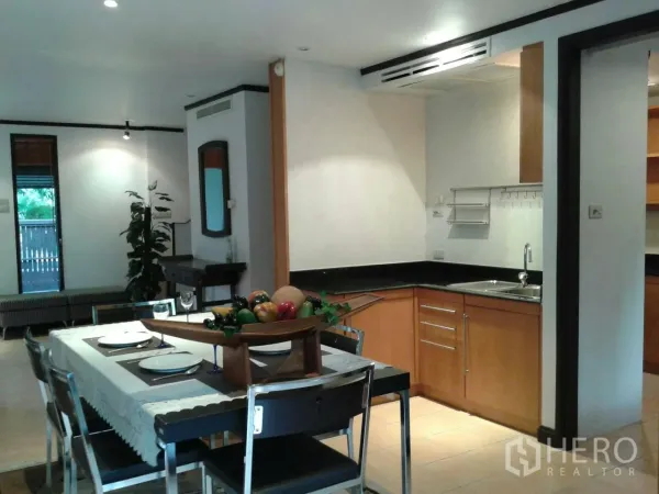 Detached House for rent in Suan Luang, Bangkok - Dining space adjoining a compact kitchenette with wood cabinets and black countertops.