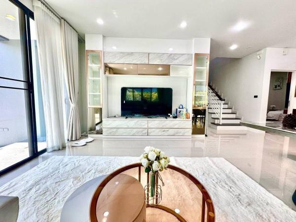 Detached House for rent in Bang Kapi, Bangkok - Living room with large TV unit, marble-style built-ins and stairs to upper floor.