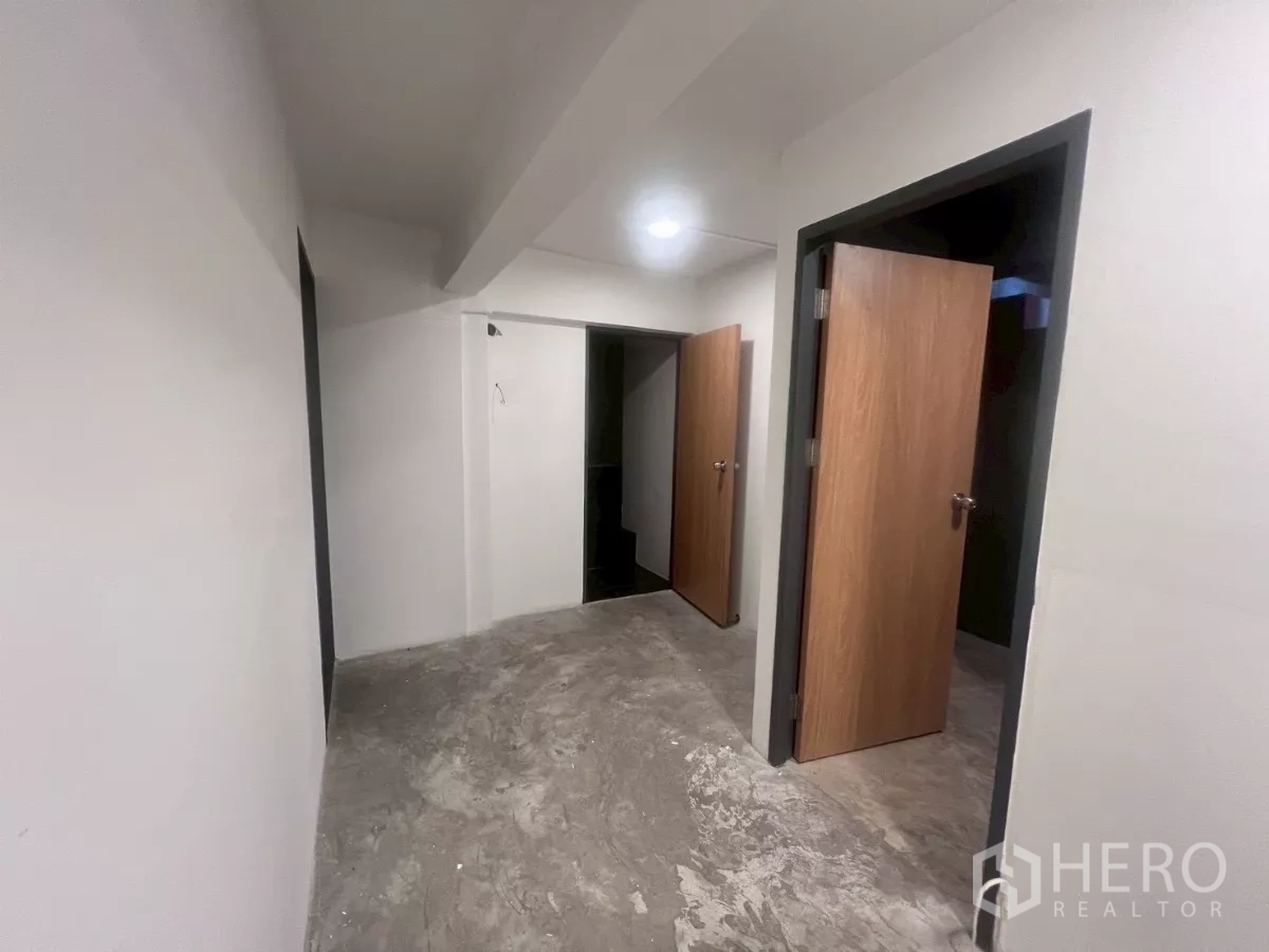 Shophouse for rent in Watthana, Bangkok - Corridor with white walls and several wooden doors leading to separate rooms.