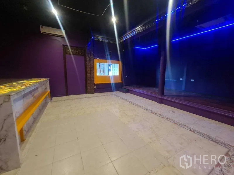 Retail Space for rent in Watthana, Bangkok - Retail room with a mirror‑like dark wall, platform stage and yellow accent window beside the counter.