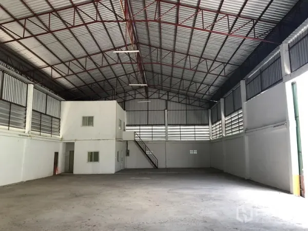 Warehouse for rent in Pathum Thani - Spacious warehouse interior featuring a high steel-truss roof, built-in office room and stair.