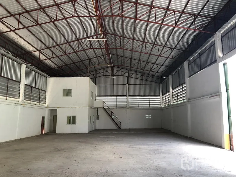 Warehouse for rent in Pathum Thani - Spacious warehouse interior featuring a high steel-truss roof, built-in office room and stair.