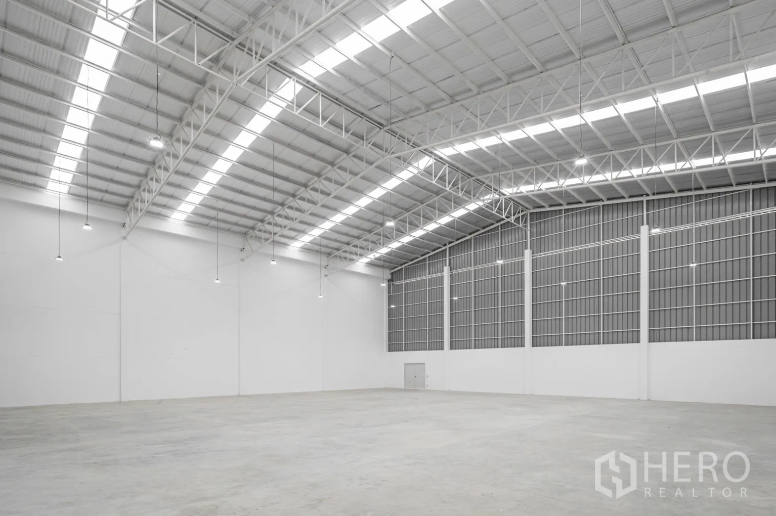 工厂 出租在Pathum Thani - 斜视角展示无柱大跨仓库与混凝土地面。