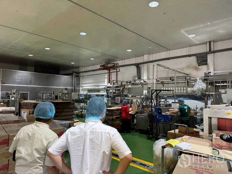 Factory for sale in Samut Prakan - Wide view of a clean manufacturing floor with stainless machinery and insulated ceiling panels.